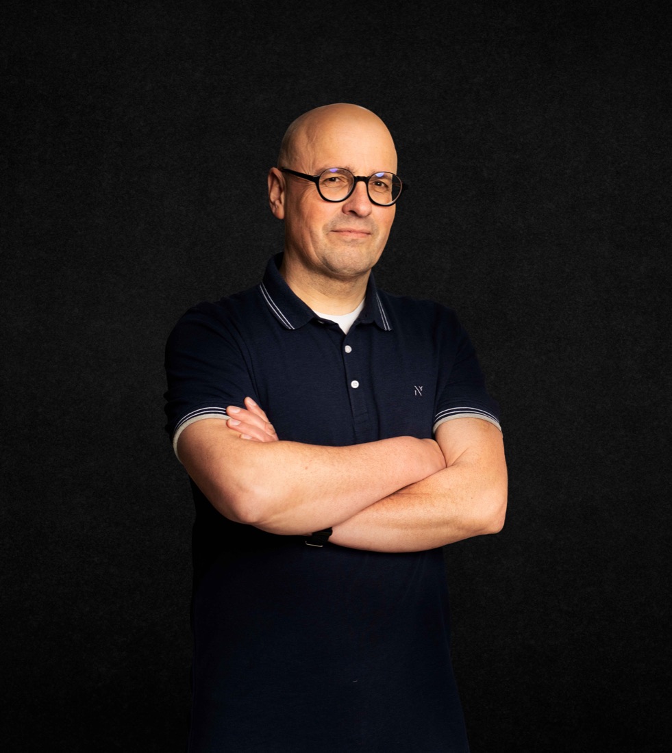Sascha Herbst mit verschränkten Armen vor dunklem Hintergrund